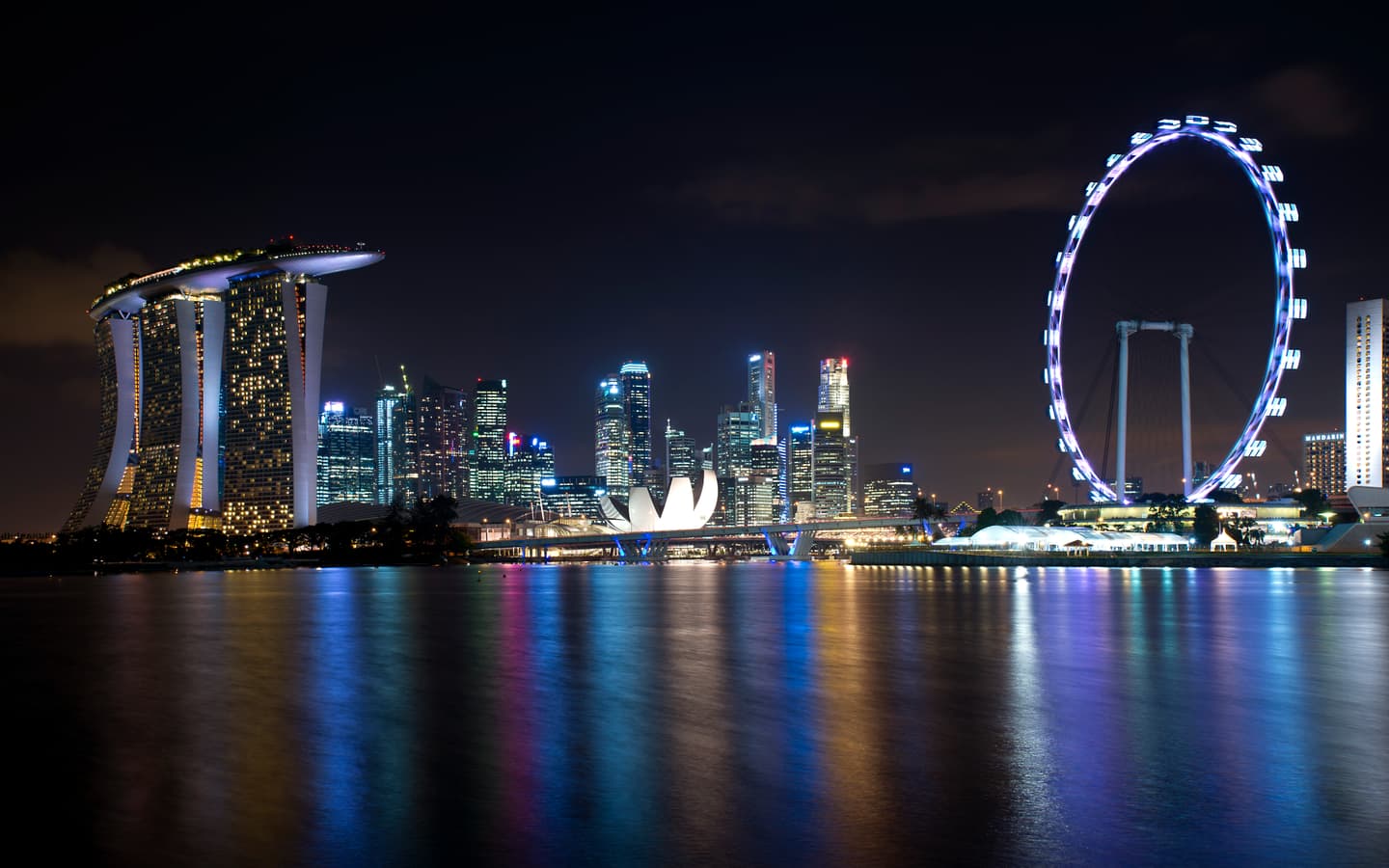 The illuminated Singapore skyline across the water from Gardens by the Bay East